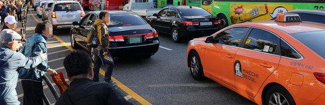 카카오 카풀 서비스에 반발하는 전국 택시업계가 파업에 돌입한 18일 오후 서울 광화문광장에서 열린 택시 생존권 사수 결의대회를 마친 후 청와대로 행진하던 참가자가 운행중인 택시에 다가가 항의하고 있다./뉴시스