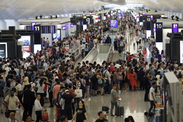 12일(현지시간) 홍콩 국제공항 출국장에 여행객들이 몰려들어 출국편 운항 정보를 확인하고 있다. 홍콩 국제공항은 이날 성명을 통해 5천여 명의 시위대가 공항에 모여 이로 인해 공항 운영이 “심각하게 방해"됐다며 홍콩발 항공편에 대한 모든 탑승 수속 서비스를 중단했다.
