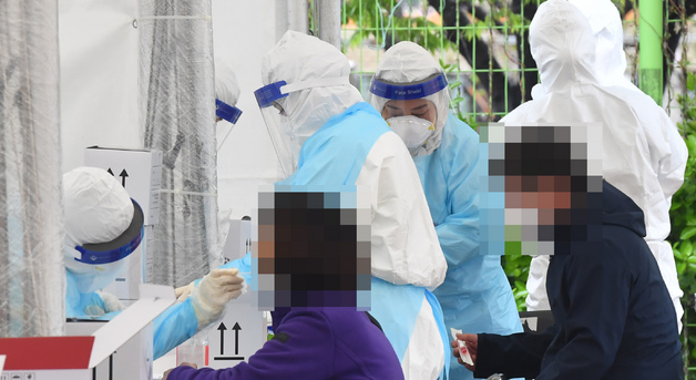 부산 사하구 신평레포츠공원에 설치된 코로나19 임시선별검사소를 찾은 시민들이 4일 오전 진단검사를 위한 검체를 채취하고 있다. 사하구는 최근 확진자가 급증하자 이 날부터 10일까지 임시선별검사소를 운영키로 했다.