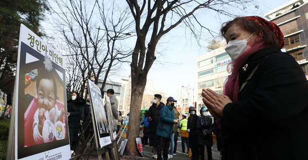16개월 여아 '정인이'의 입양부모 5차 공판이 열리는 지난달 3일 서울 양천구 서울남부지방법원 앞에서 한 시민이 정인이 사진을 보며 기도하고 있다.