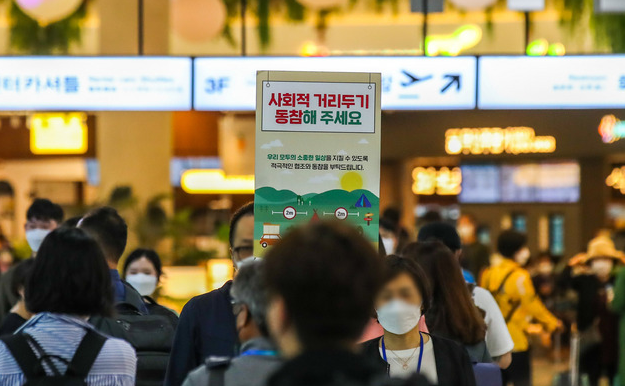 지난 5월 13일 오전 제주국제공항 1층 도착장에서 공항 관계자가 '사회적 거리두기 동참' 호소 팻말을 들고 있다.