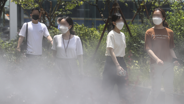  폭염이 이어지고 있는 15일 오후 서울 중구 명동에서 시민들이 쿨링포그 앞을 지나며 더위를 식히고 있다.
