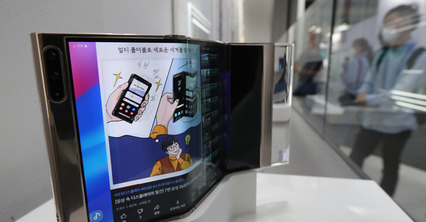 '2021년 한국디스플레이 산업전시회(IMID 2021)'가 개막한 25일 서울 삼성동 코엑스에서 삼성디스플레이 전시관을 찾은 관람객들이 S자 형태로 두번 접는 '플렉스 인앤아웃 폴더블'을 보고 있다.