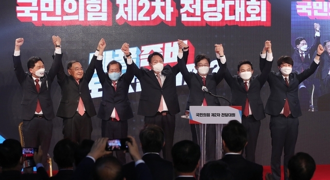  국민의힘 대선 후보로 선출된 윤석열 후보가 5일 서울 용산구 백범김구기념관에서 열린 국민의힘 전당대회에서 손을 들어 인사하고 있다. 왼쪽부터 김기현 원내대표, 정홍원 선거관리위원장, 홍준표 후보, 윤 후보, 유승민 후보, 원희룡 후보, 이준석 대표.