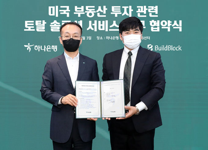 하나은행, ㈜빌드블록과 미국 부동산 투자 관련 토탈 솔루션 서비스 제공을 위한 업무협약 체결. 김기석 하나은행 자산관리그룹 부행장(사진 왼쪽)과 정지원 ㈜빌드블록 대표(사진 오른쪽)이 협약서를 들고 기념촬영을 하고 있다. ⓒ 파이낸셜데일리 / 하나은행