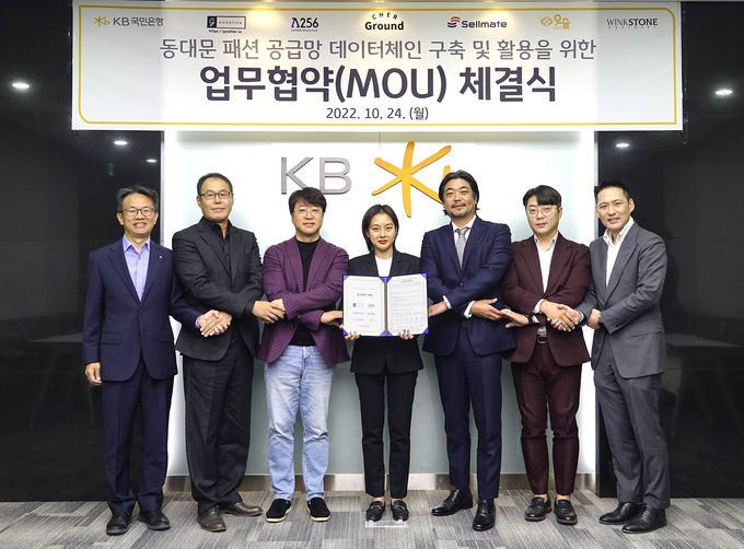 24일 서울시 영등포구 KB국민은행 여의도 IT센터에서 열린 동대문 패션 공급망 데이터체인 구축 및 활용을 위한 업무협약식에서 (왼쪽부터) 윤진수 KB국민은행 테크그룹 대표, 이한수 굿티어 대표, 박재현 람다256 대표, 이연 쉐어그라운드 대표, 서원준 셀메이트 대표, 조형일 위아더 대표, 권오형 윙크스톤파트너스 대표가 기념촬영을 하고 있다. ⓒ 파이낸셜데일리 / KB국민은행