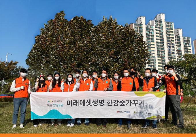 이촌 한강공원에 2023년까지 면적 3천㎡에 달하는 ‘미래에셋생명 숲’을 만든다. 봉사에 참석한 미래에셋생명 임직원들이 기념촬영을 하고 있다. ⓒ 파이낸셜데일리 / 미래에셋생명