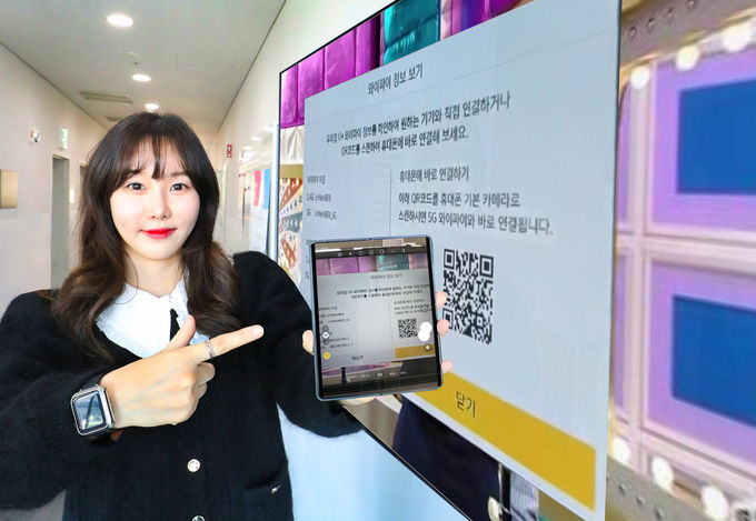  LG유플러스 직원이 U<sup>+</sup>tv 속 QR코드를 스마트폰 카메라로 촬영해 WiFi를 연결하고 있는 모습 ⓒ 파이낸셜데일리 / LG유플러스