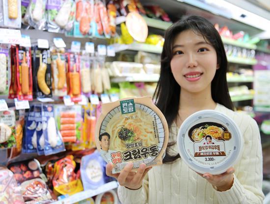 모델이 GS25에서 '편스토랑 장민호의 꾸덕명란 크림우동'과 '혜자로운 바삭킹튀김우동' 상품을 들고 있다. ⓒ 파이낸셜데일리 / GS25