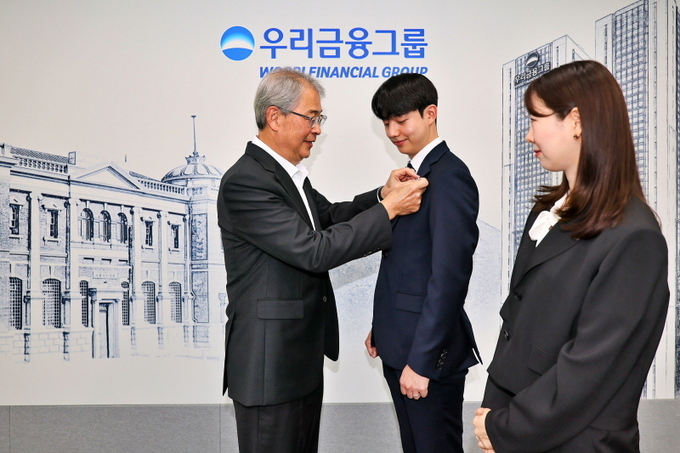 우리금융그룹 임종룡 회장이 그룹의 새 가족이 된 동양생명·ABL생명 직원에게 디지털 선도의 의미가 담긴 새로운 그룹 보조휘장을 달아주고 있다. (사진=우리금융그룹 제공)